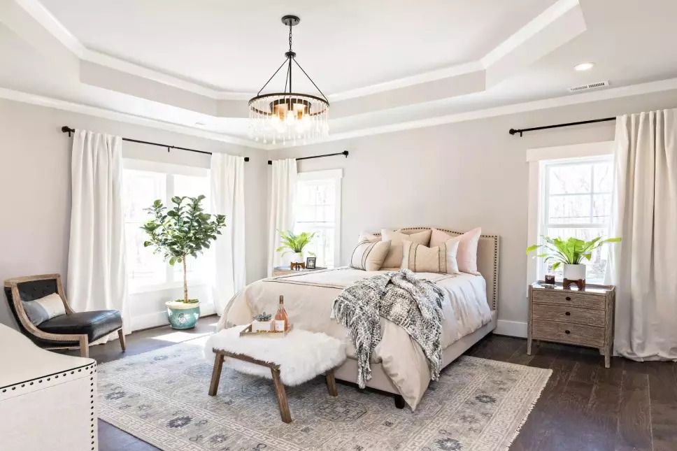Bright bedroom with natural light from two windows framing the bed.