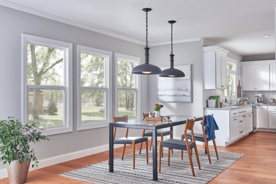 A large, open kitchen with white and gray tones and decor, allowing in lots of natural light.