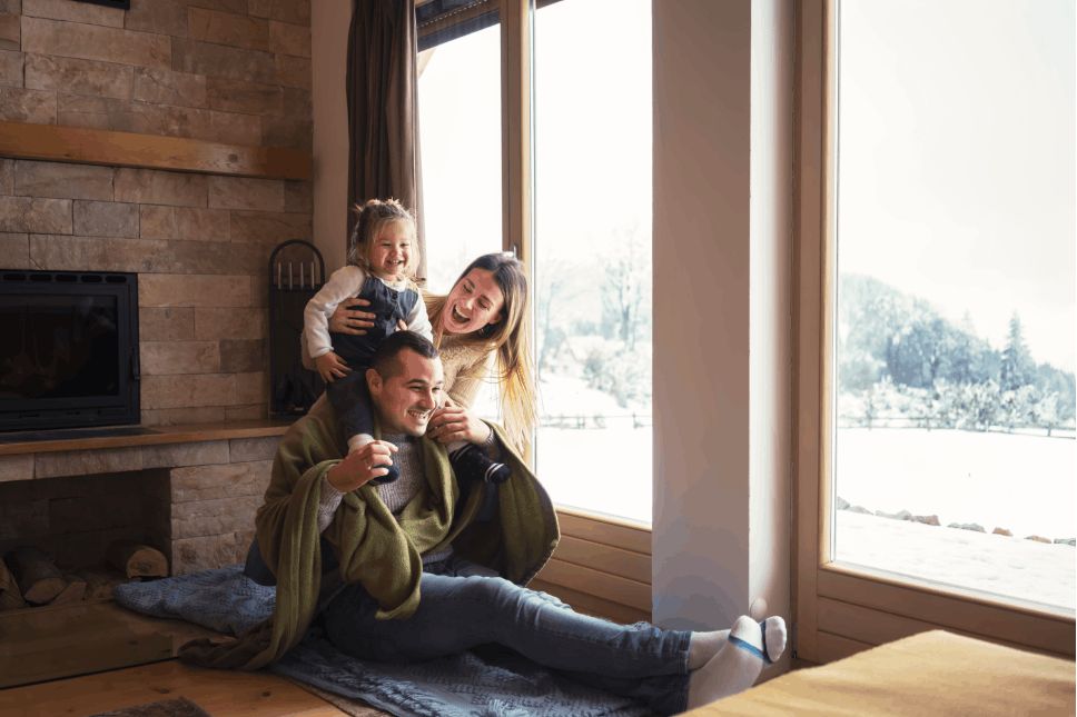 Family inside a living room with a wintry landscape outside the windows.