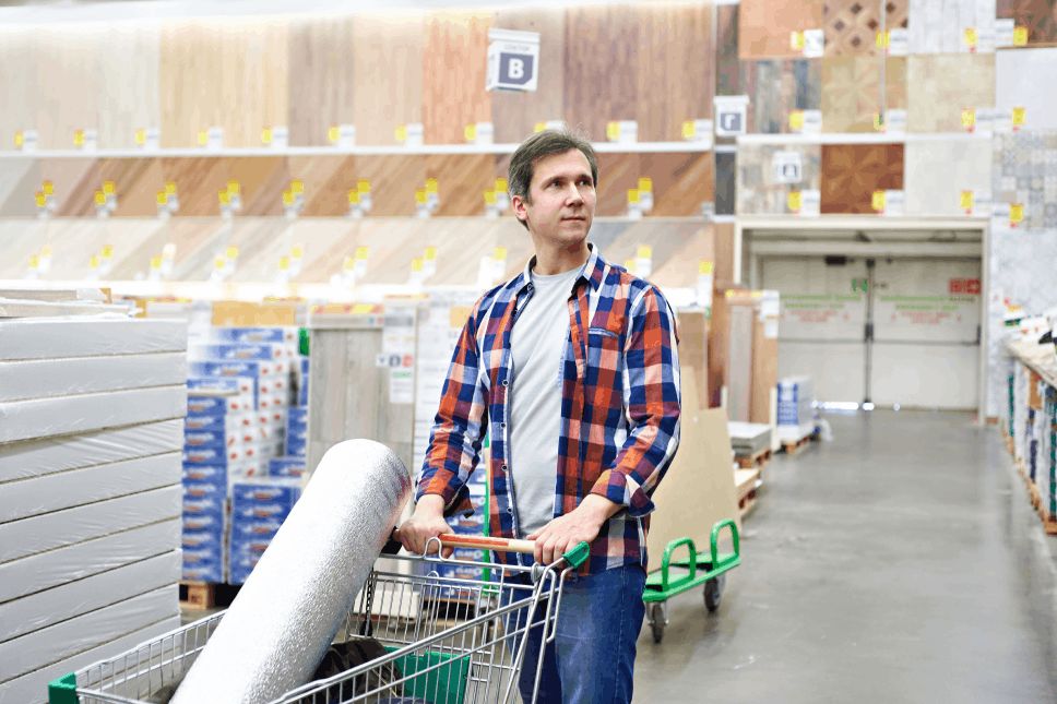 Man with a shopping cart inside a home improvement store.