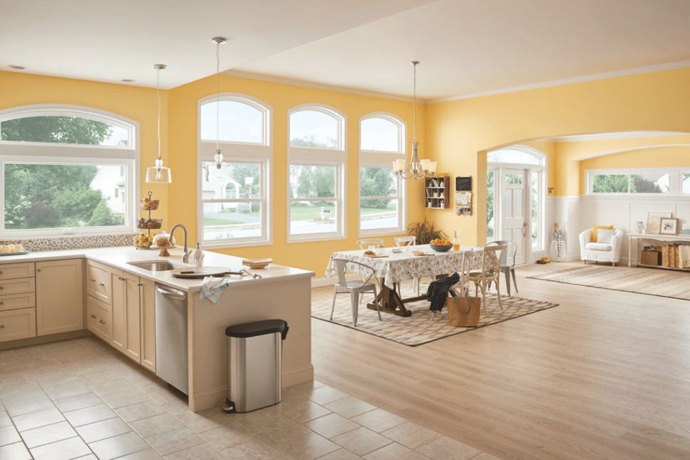 Kitchen & dining room of home with yellow walls and double-hung, architectural, & sliding windows.