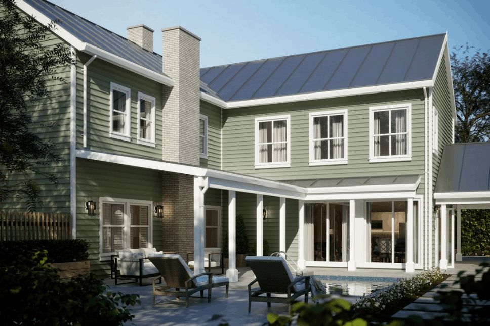 Back patio of a home with light green siding and a small pool.