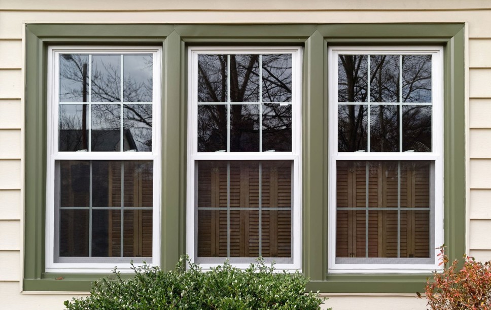 Three vinyl windows with interior window shutters on the side of a house.