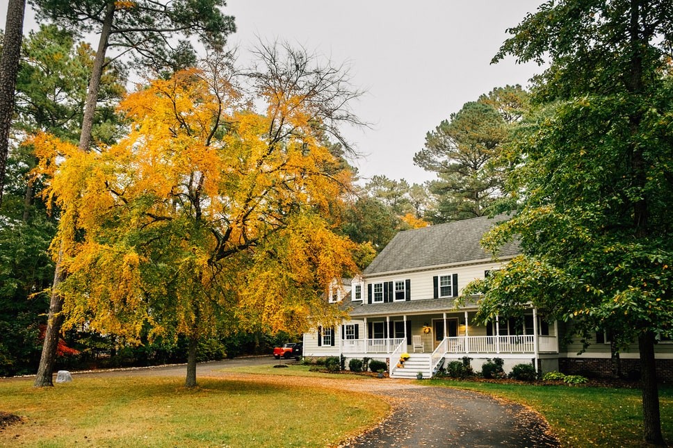 A colonial-style home surrounded by large and colorful trees.